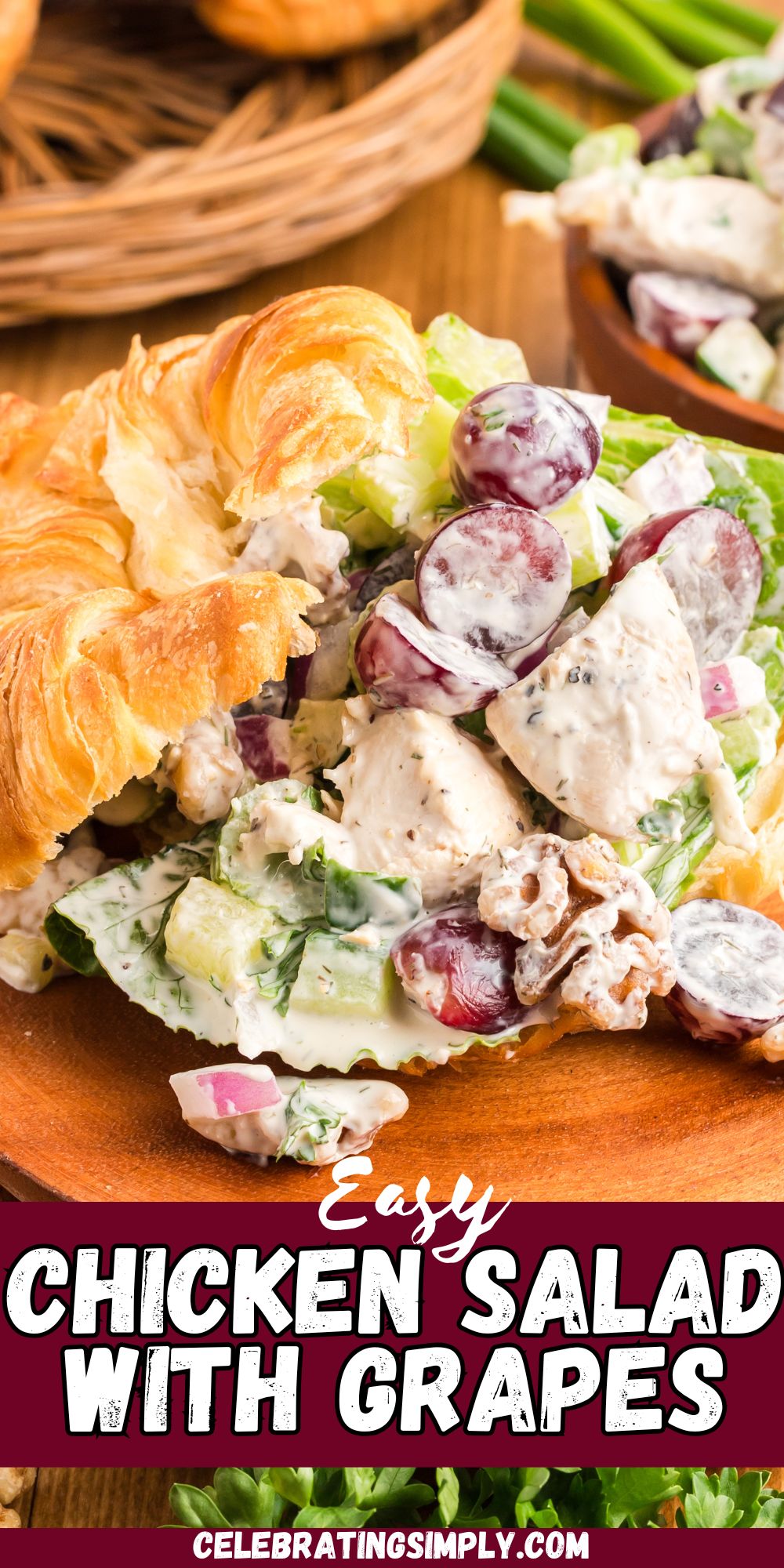 Creamy chicken salad with nuts and grapes, in a croissant on a wooden plate.