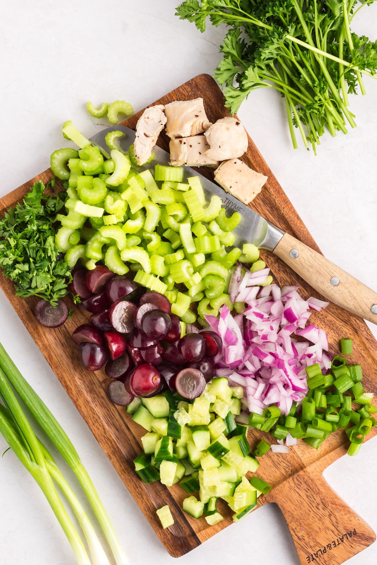 Recipe ingredients chopped on a wooden cutting board, before being mixed into a bowl. 