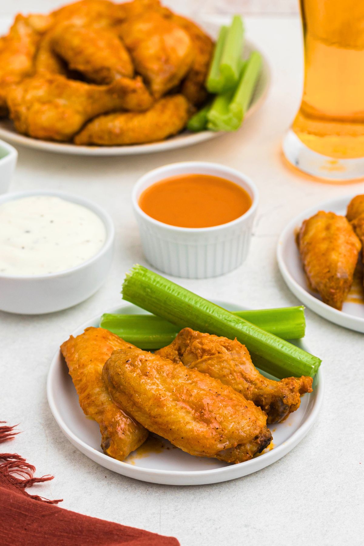 Three chicken wings tossed in buffalo sauce on a white plate with celery sauce.