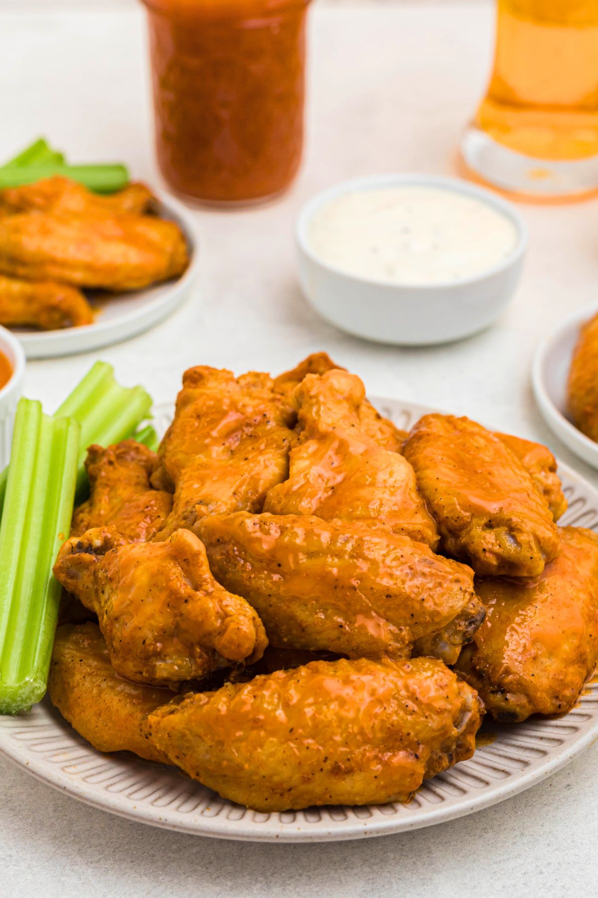 Golden chicken wings on a white plate with celery sticks.