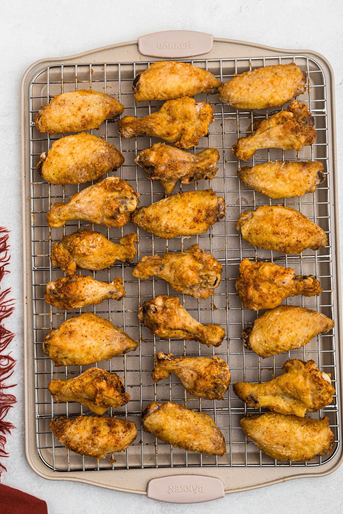 Golden and crispy baked chicken wings on a wire rack over a baking sheet after being baked in the oven. 