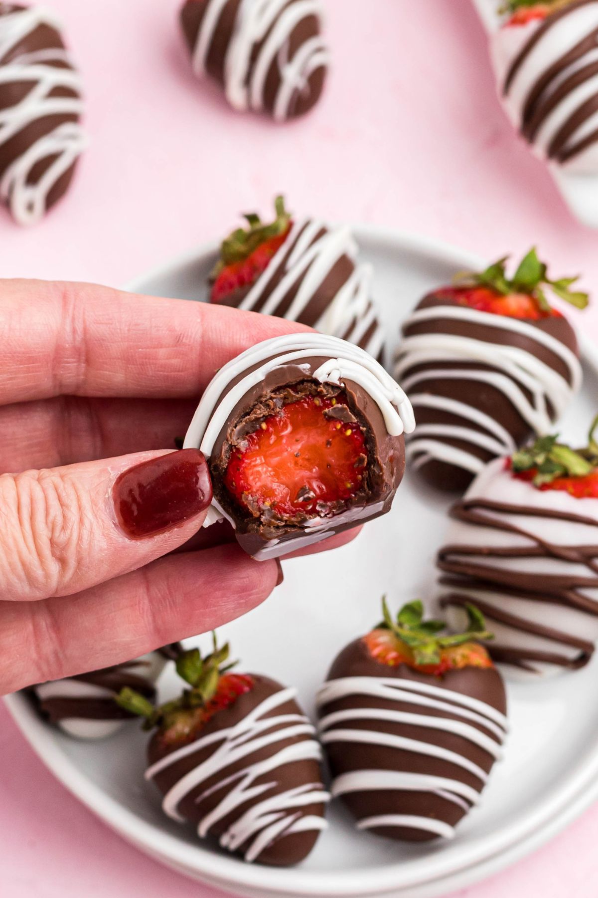 One chocolate dipped strawberry being held after a bite has been removed showing the center. 