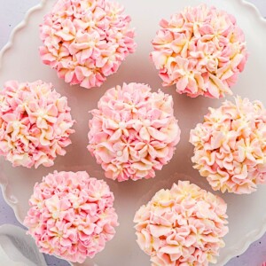 Pink and white pretty hydrangea cupcakes on a white baking dish.