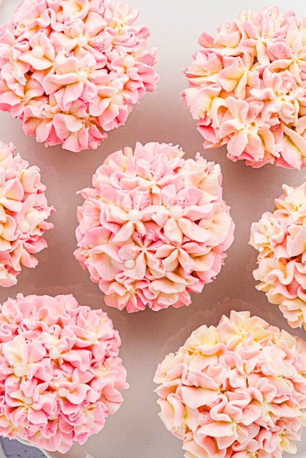 Pink and white pretty hydrangea cupcakes on a white baking dish.