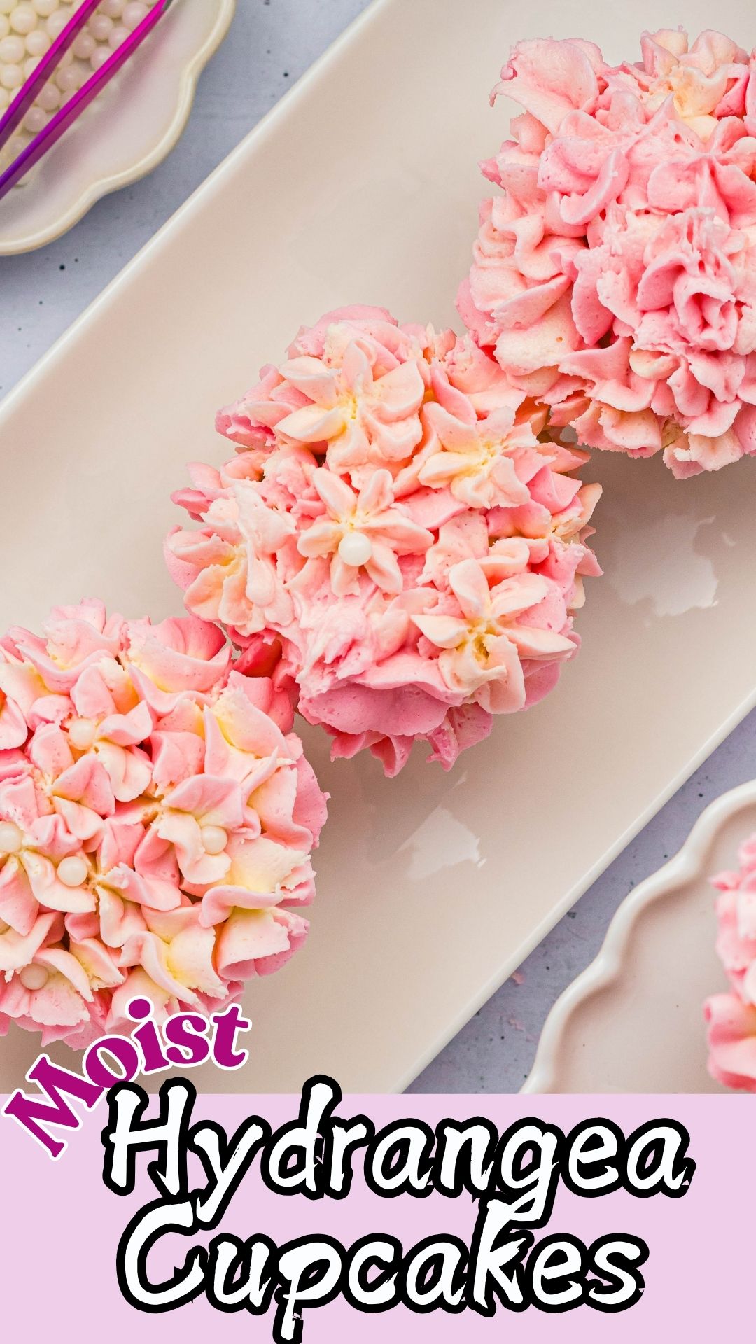 Pink and white frosted cupcakes on a white rectangle plate.