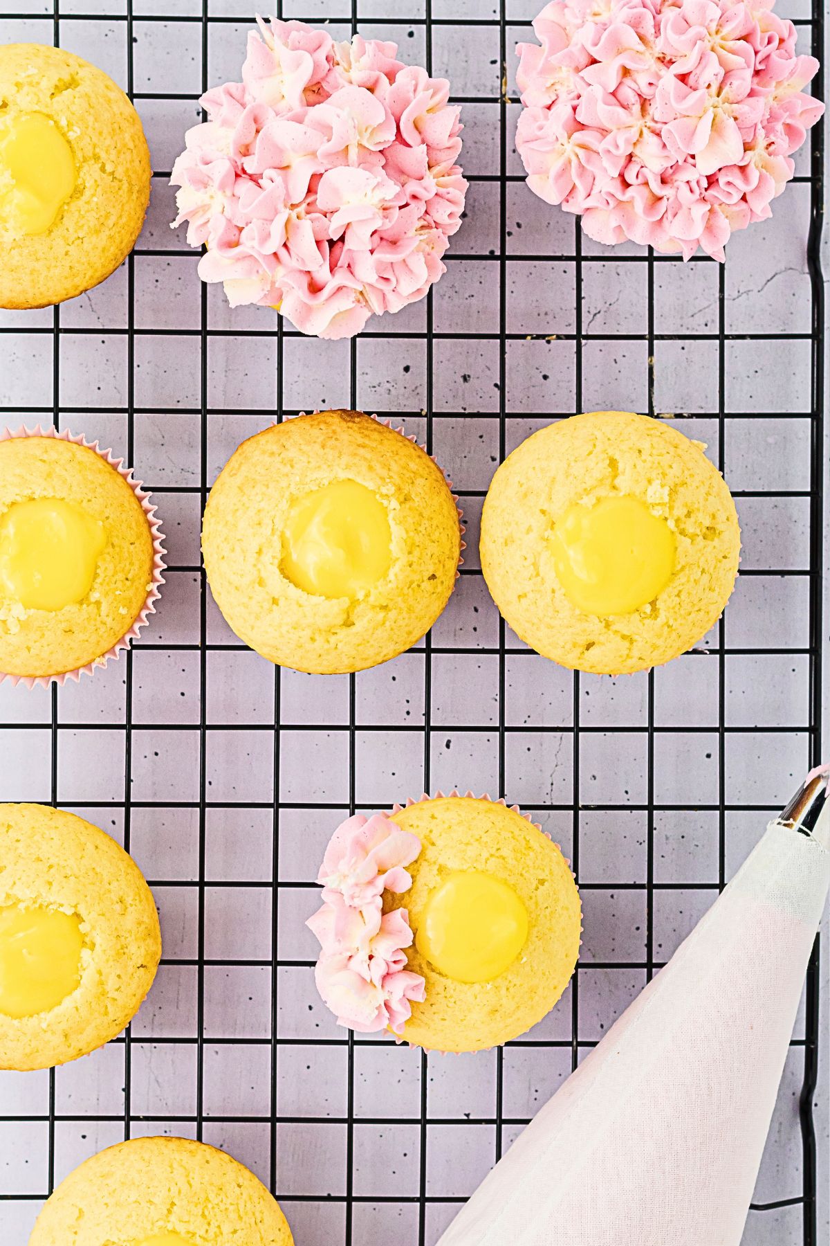 Vanilla cupcakes being frosted with pink and white combined frosting to make hydrangea cupcakes. 