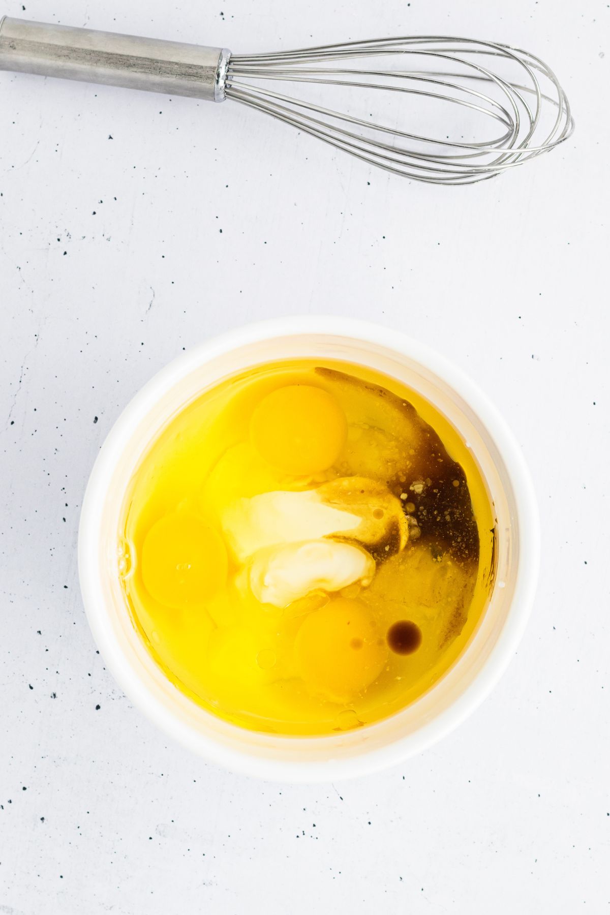 Eggs being mixed with other ingredients in a white bowl. 