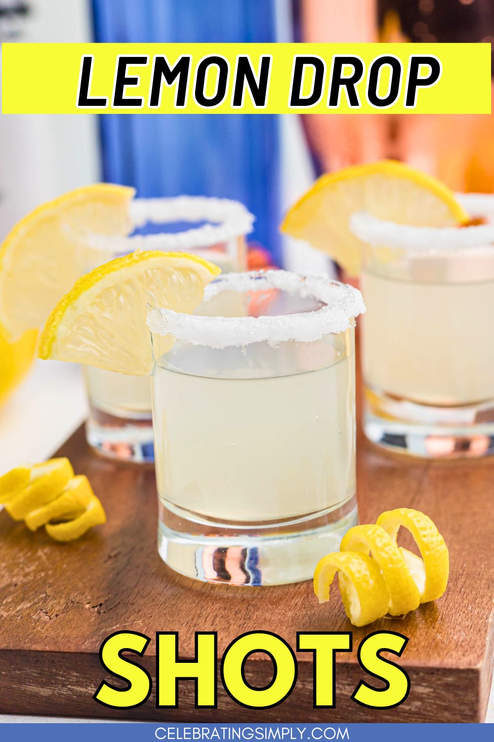 Sugar rimmed shot glass with lemon wedge for garnish, and lemon curls in front of glass, after being filled with lemon drop shots.