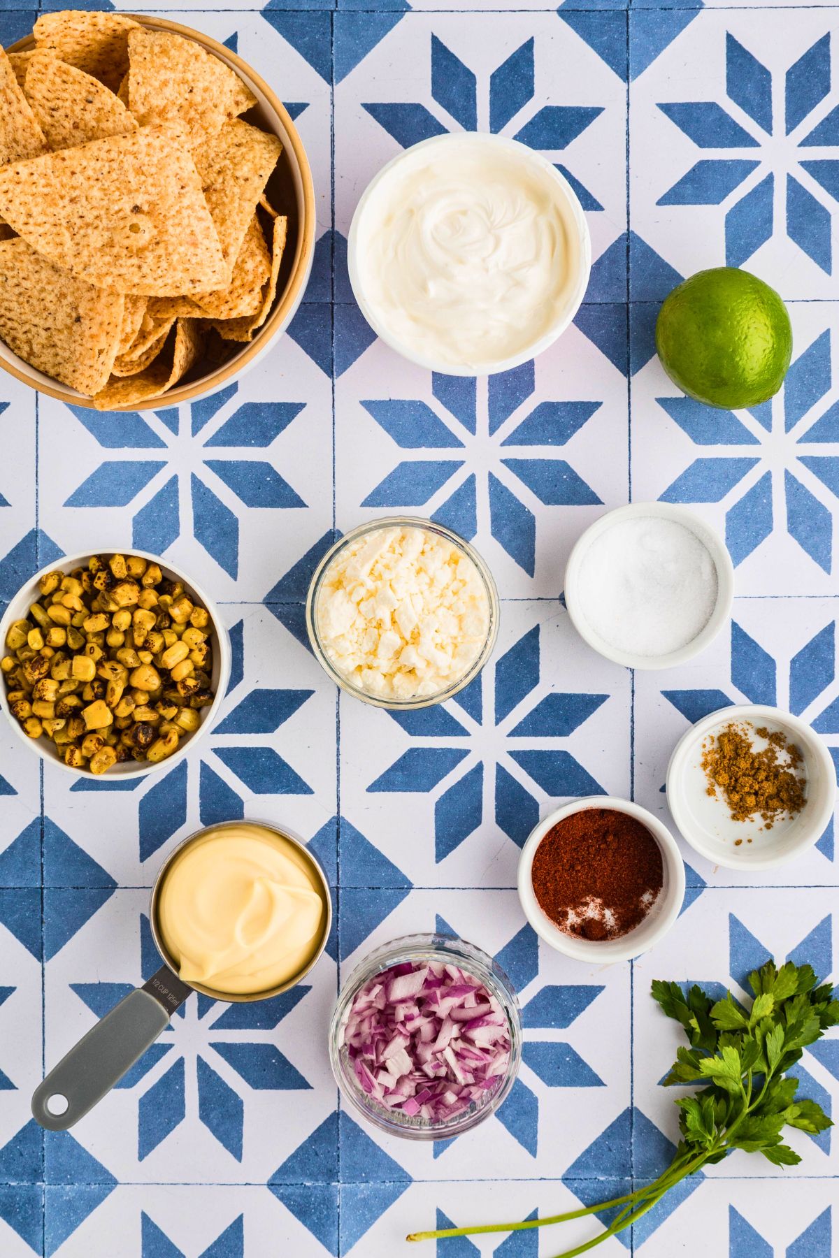 Ingredients measured into small bowls on a blue and white tiled table. 