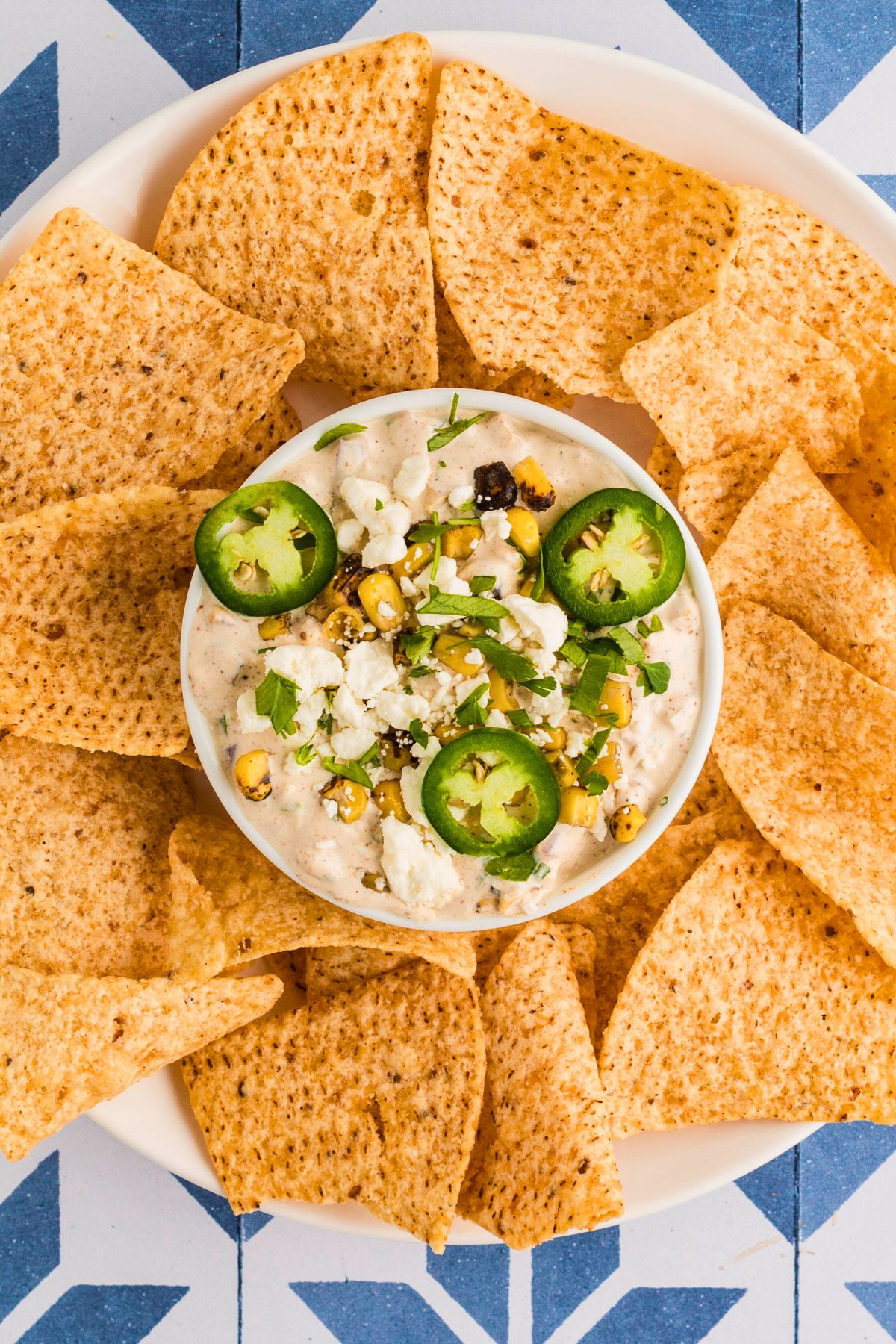 Mexican street corn dip in a small bowl surrounded by tortilla chips. 