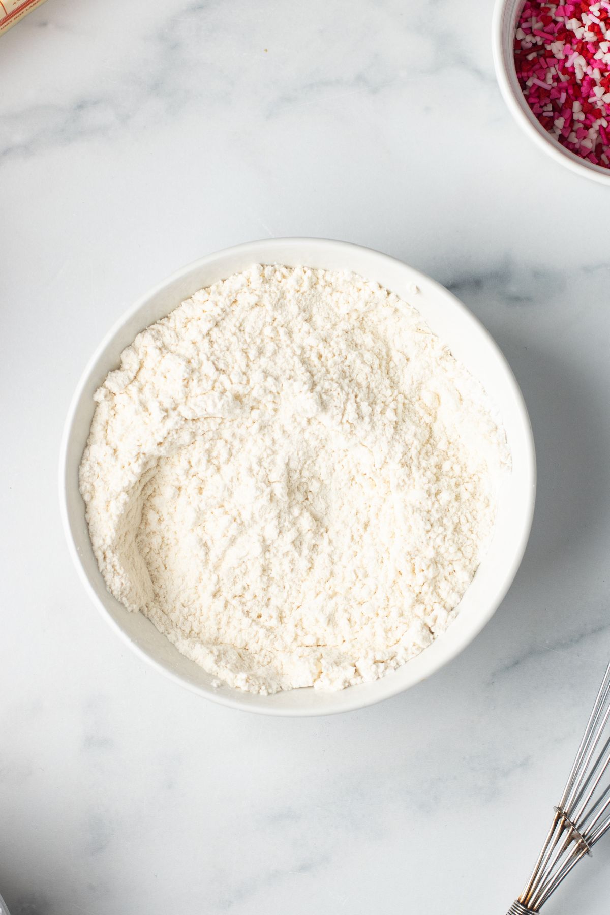 Dry ingredients for cupcakes mixed in white mixing bowls. 