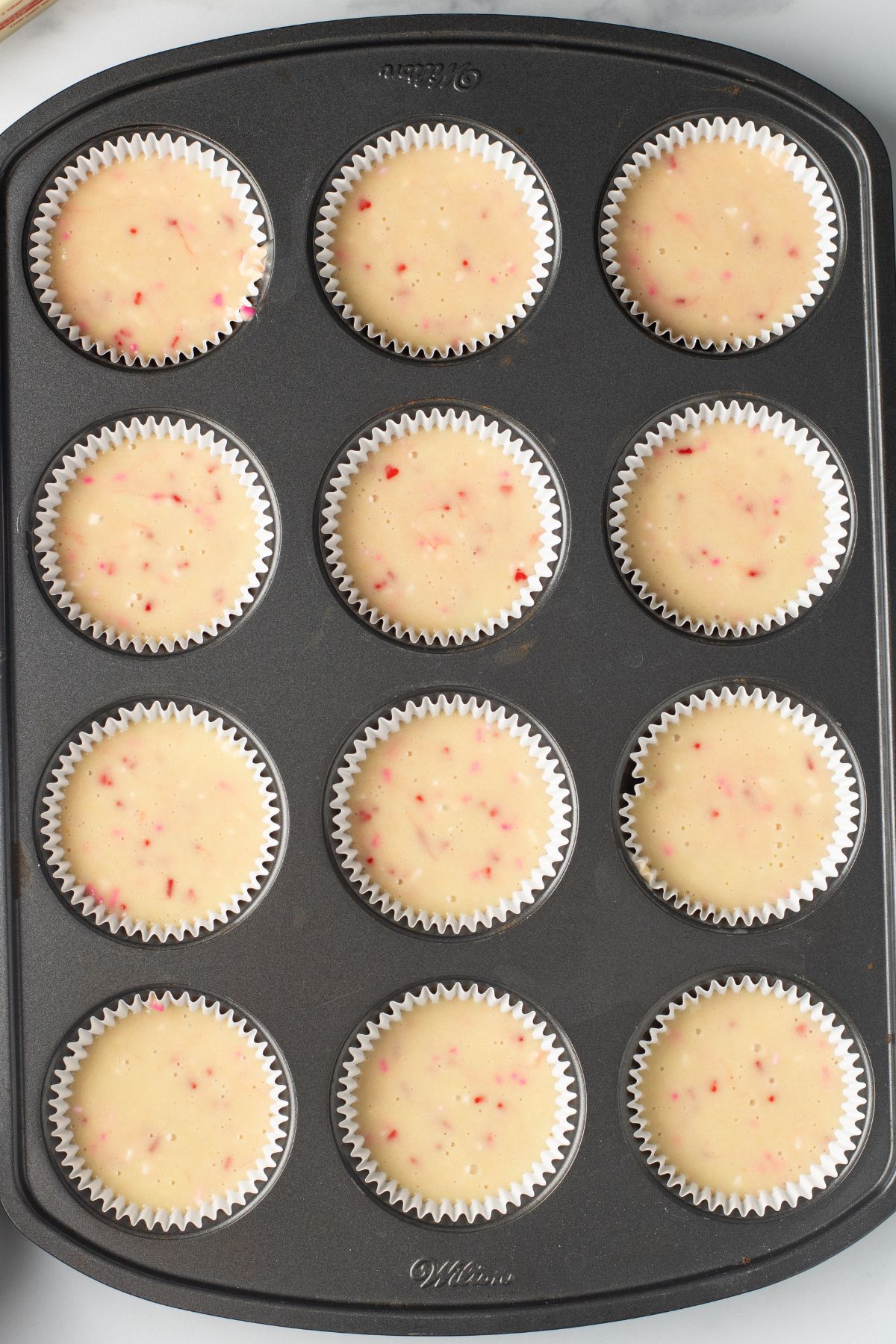 Cupcake batter in a muffin tin before baking. 