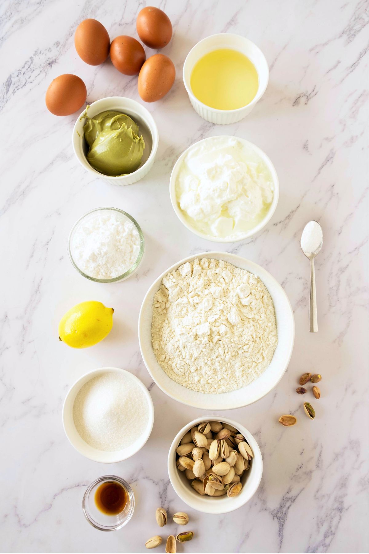 Ingredients needed to make cake measured out in white bowl on a marble table. 