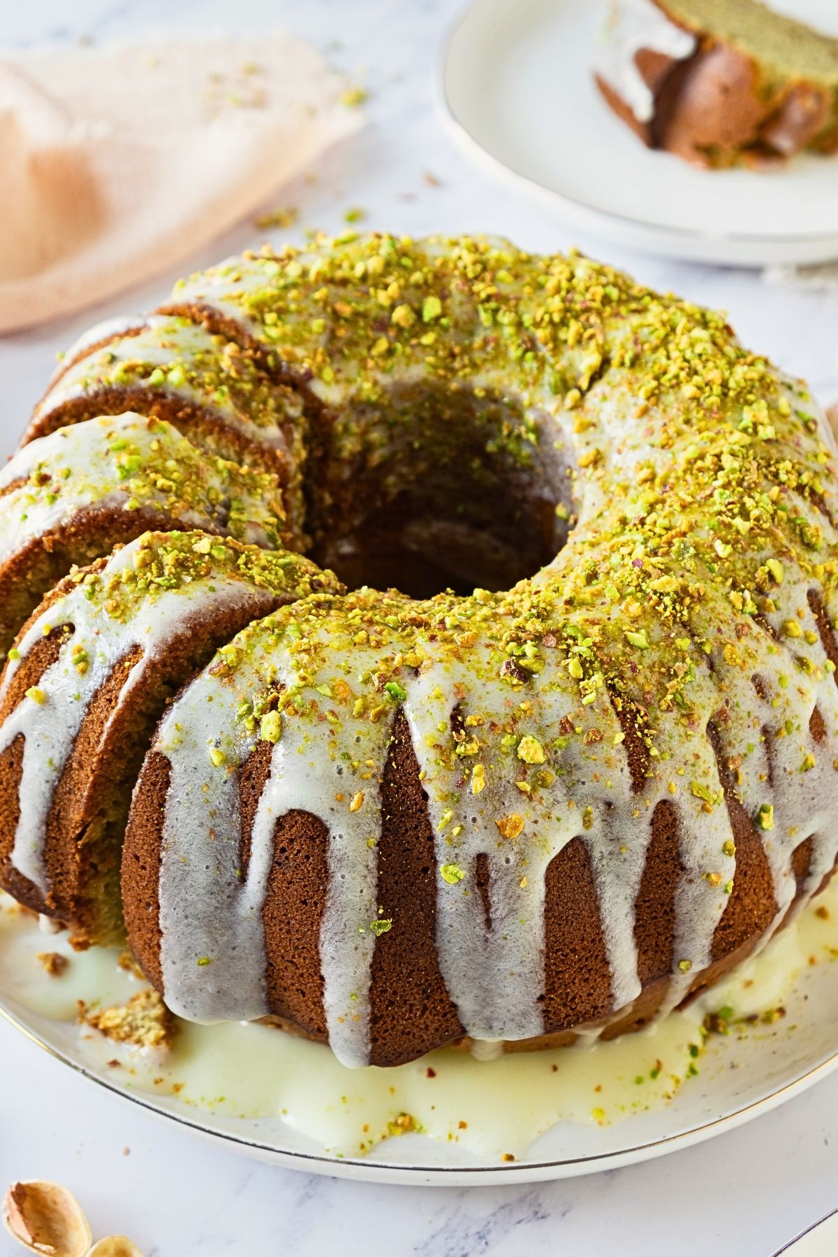 Bundt cake on a platter with a few slices made into the left side of the cake. 