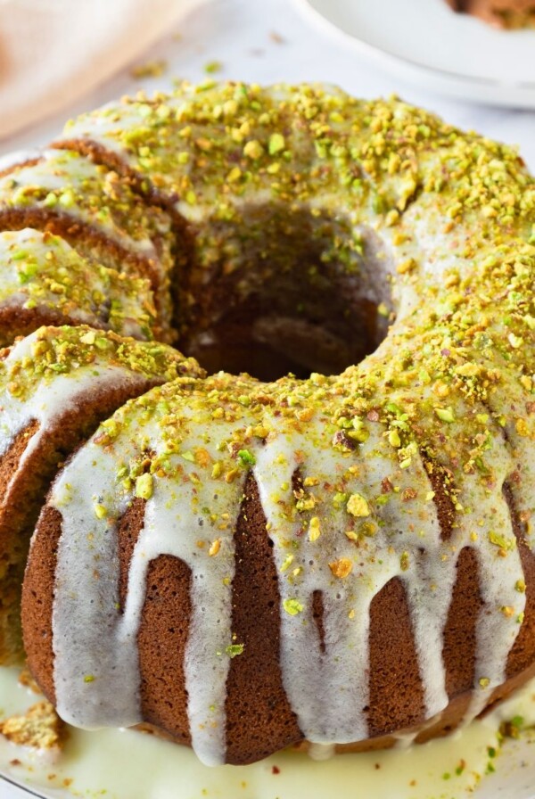 Bundt cake on a platter with a few slices made into the left side of the cake.