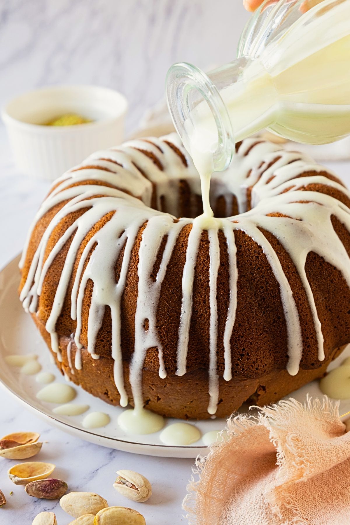 White icing being drizzled over a Bundt cake. 