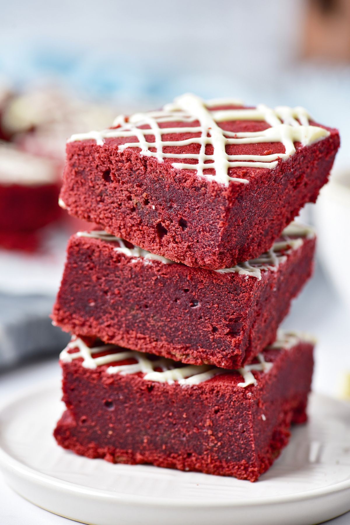 Red velvet brownies cut into squares and stacked on a small white plate. 