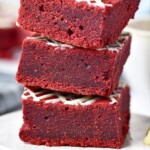 Red velvet brownies cut into squares and stacked on a small white plate.