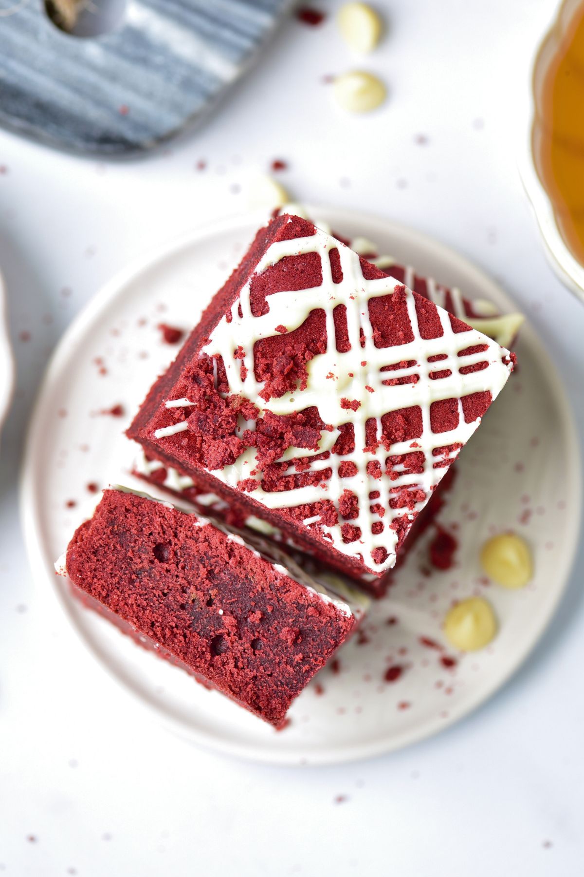 Red brownie cut and served on a small white plate with white chips on the table.