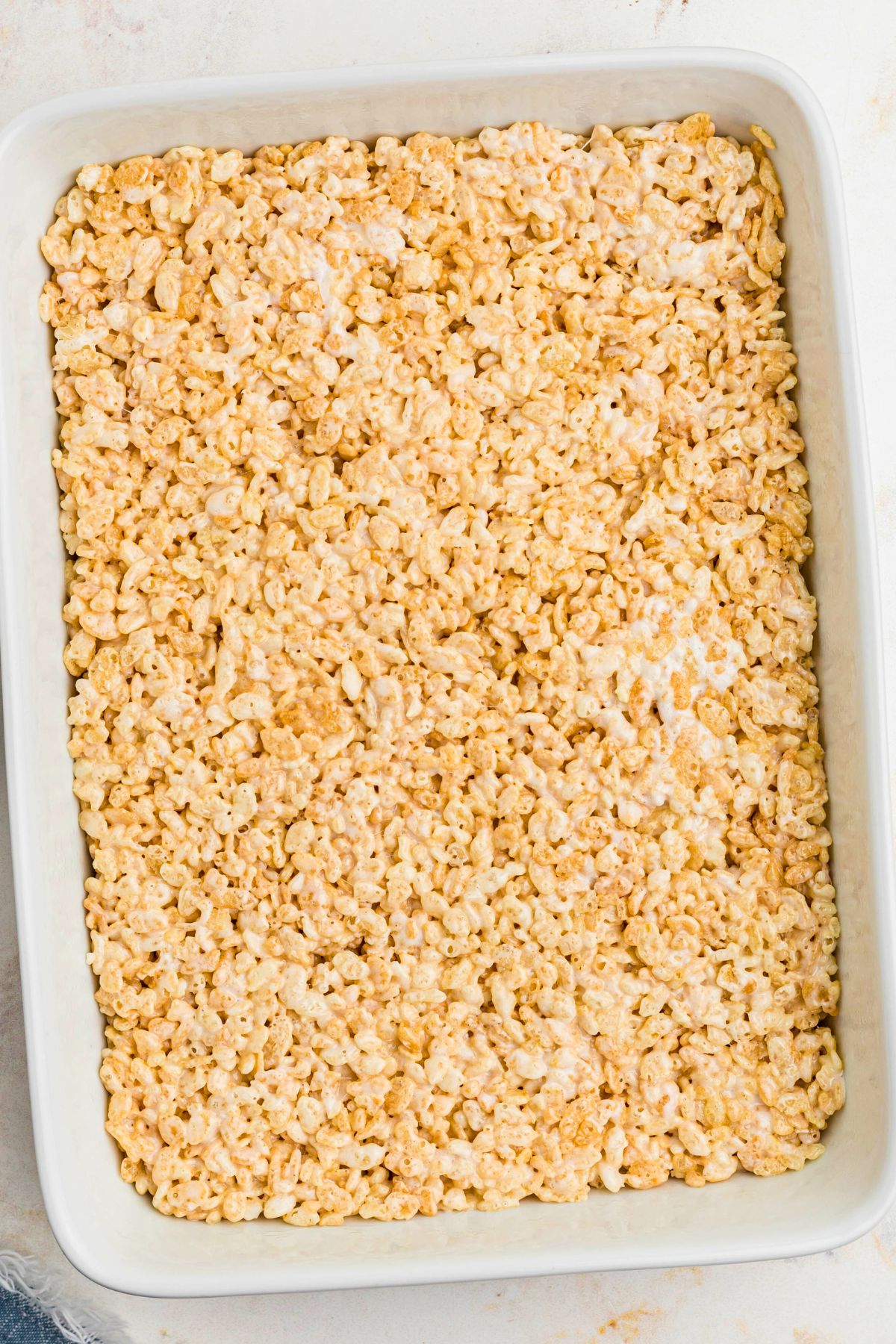 Rice krispie treats in a white casserole dish, pressed down. 