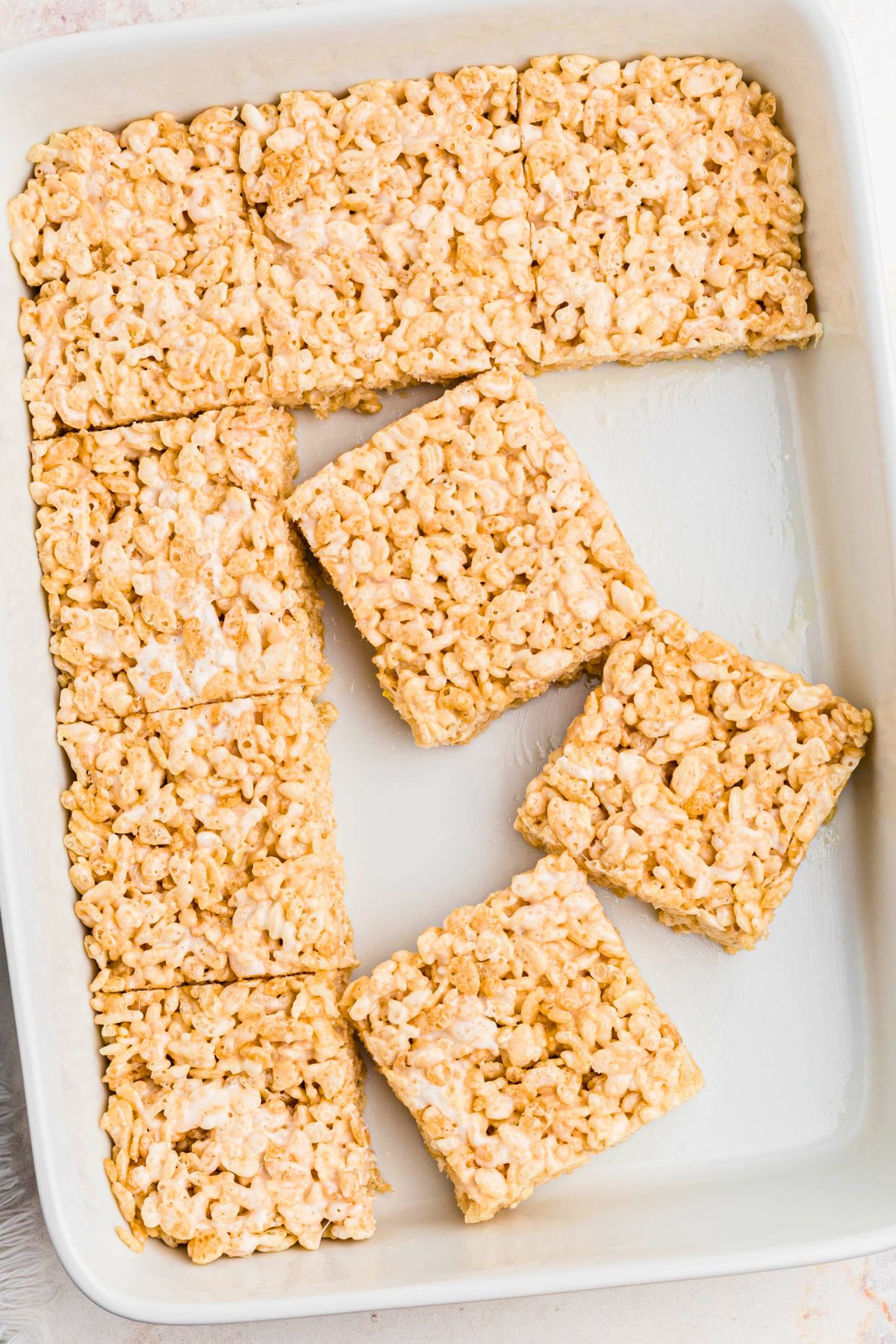 Rice krispie treats cut into squares in a white 9x13 dish. 