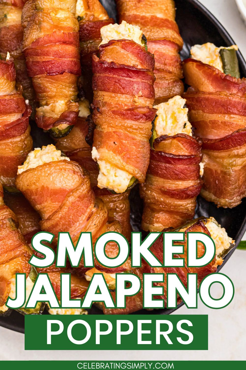 Smoked bacon wrapped jalapeno poppers stacked on a black plate.