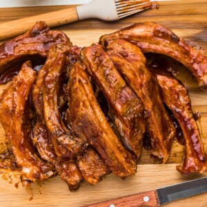 Juicy baby back BBQ ribs on a wooden cutting board.