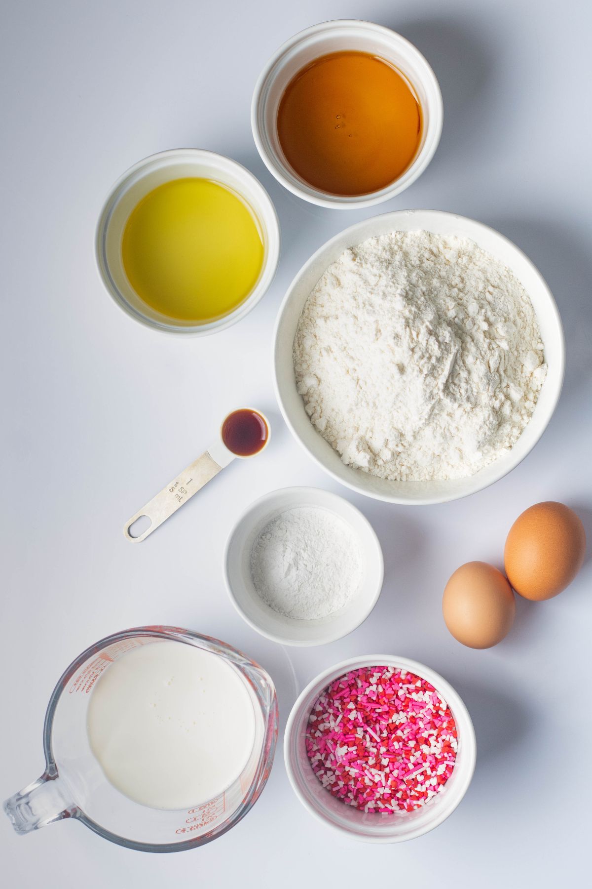 Ingredients measured in small white bowls on a white marble table. 