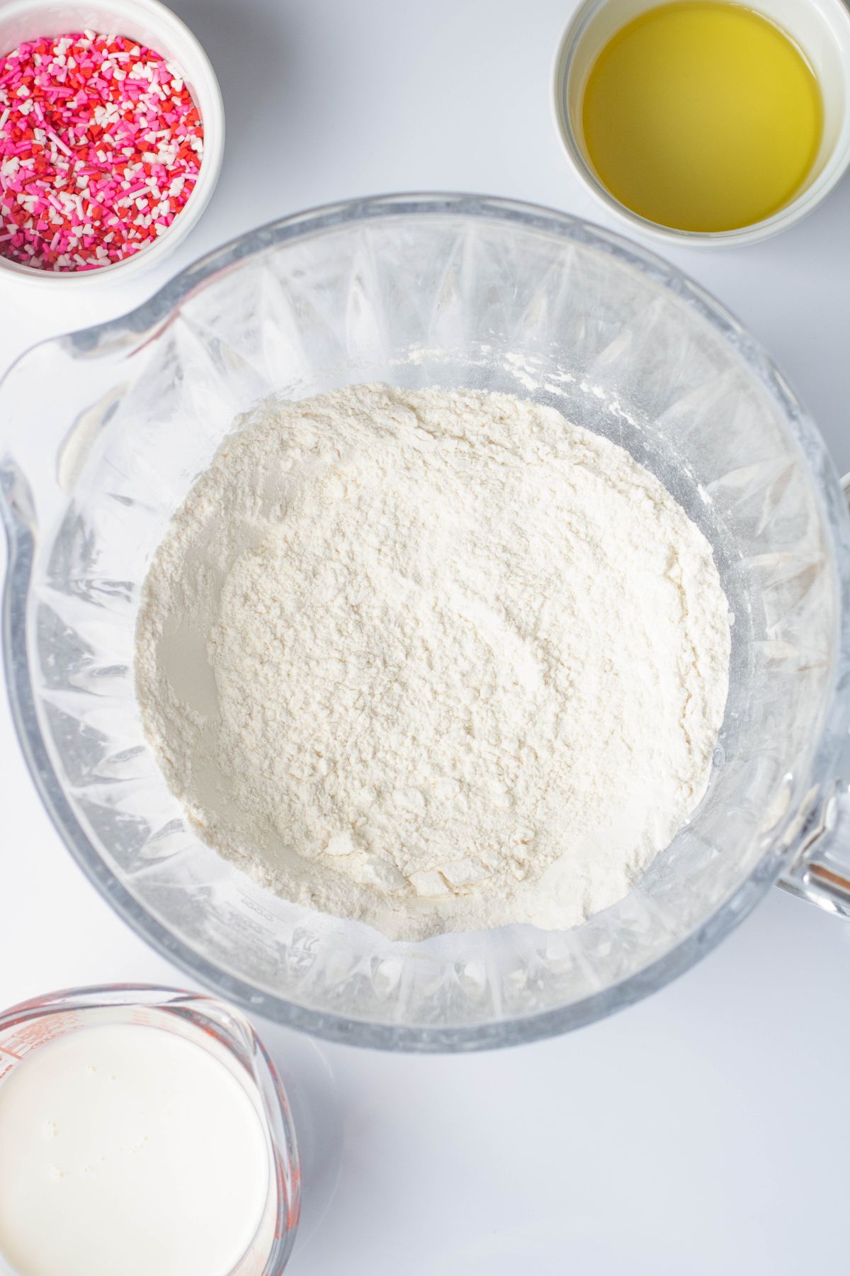 Ingredients in clear bowl, being mixed together before adding in sprinkles. 