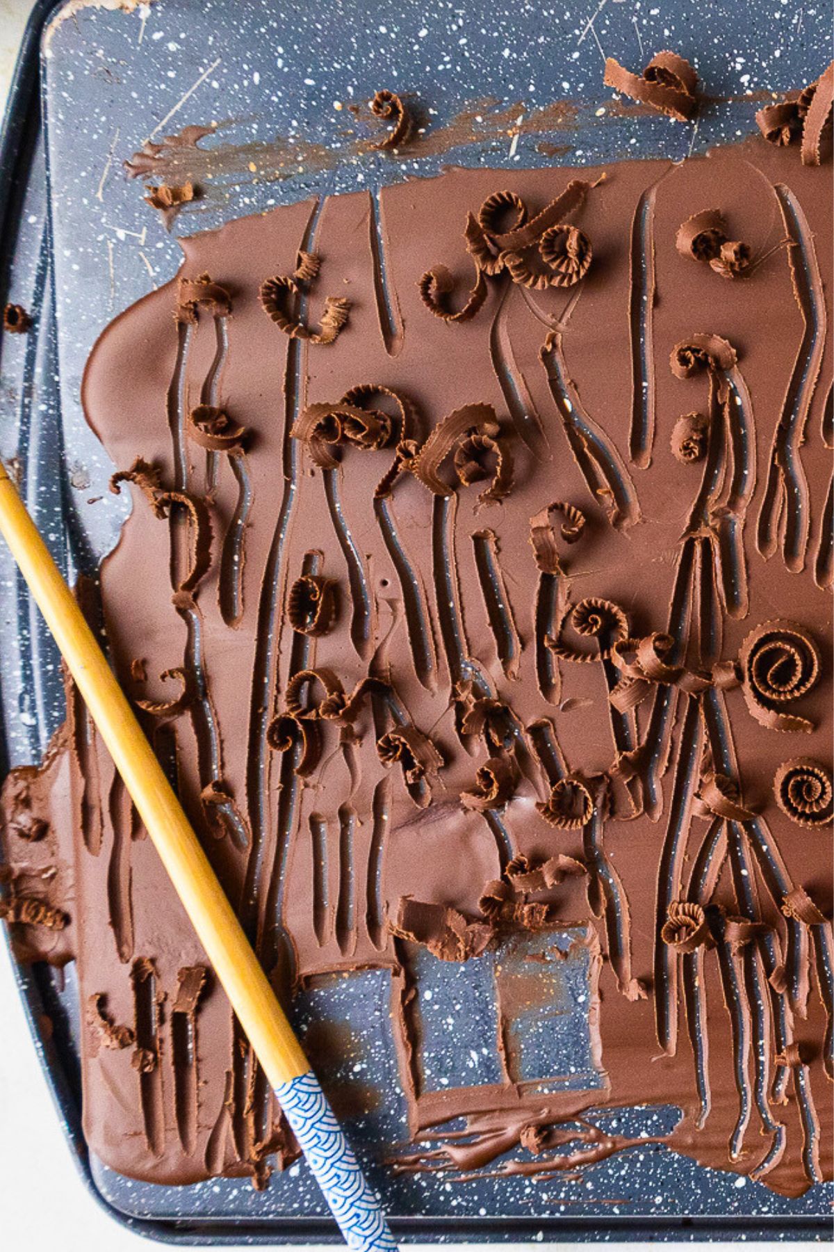 Chocolate spread onto a baking sheet, making chocolate curls. 