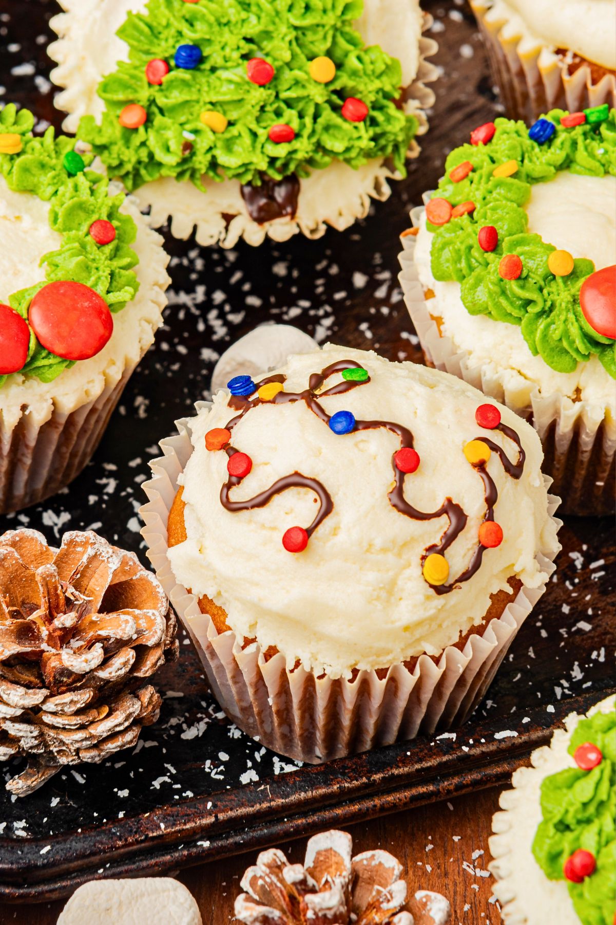 Cupcakes with frosting and holiday festive decorations piped on top. 