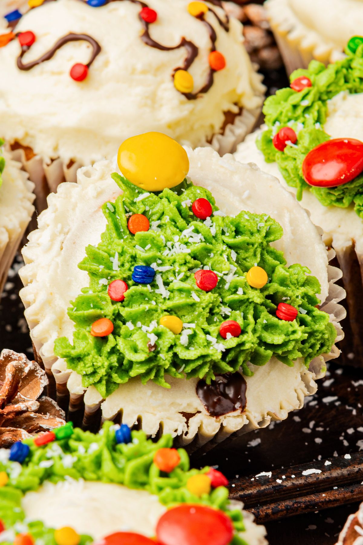 Christmas cupcakes with trees, wreaths, and lights decorations, on a table.