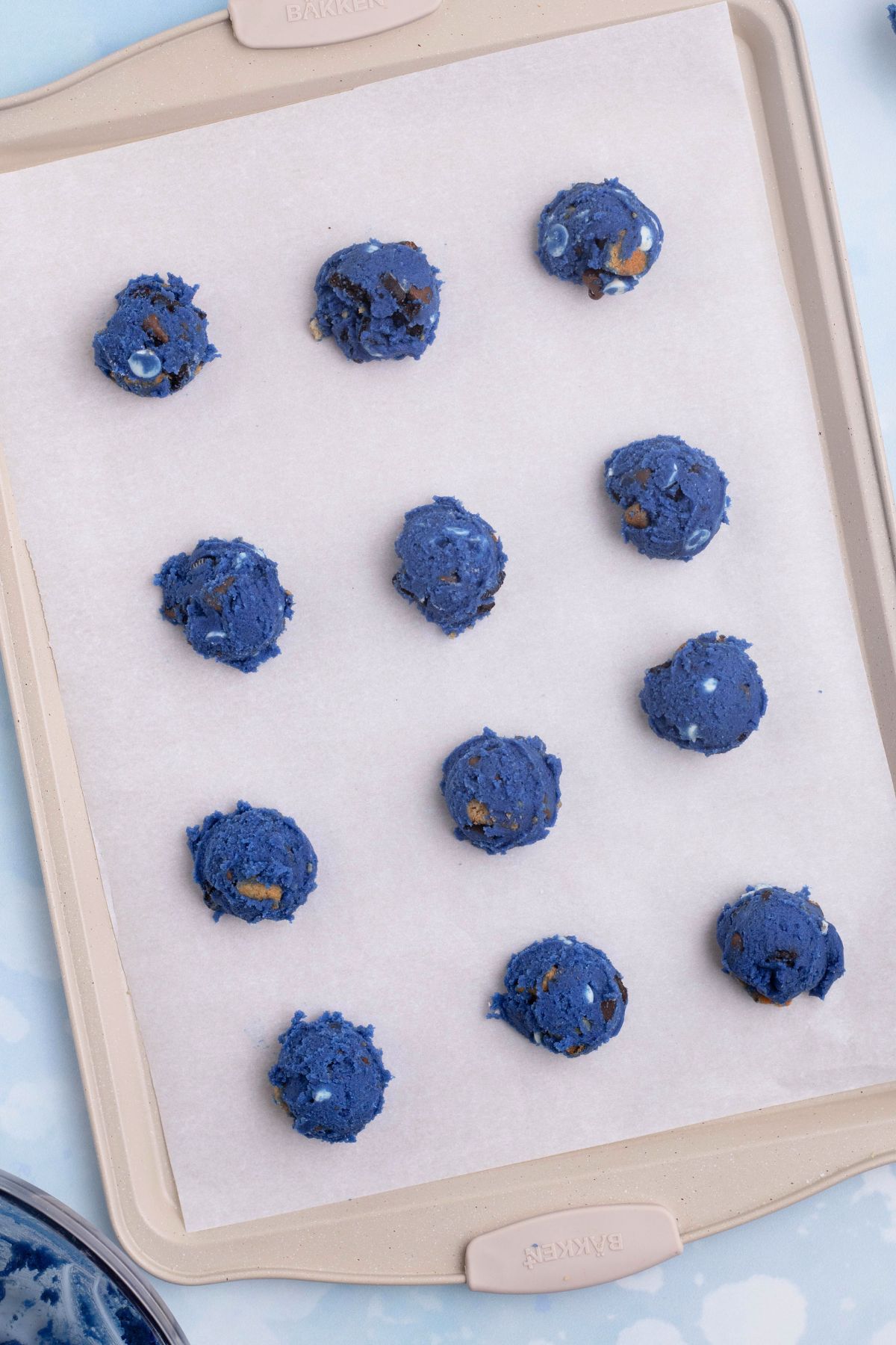 Cookie dough scooped onto a baking sheet lined with parchment paper.