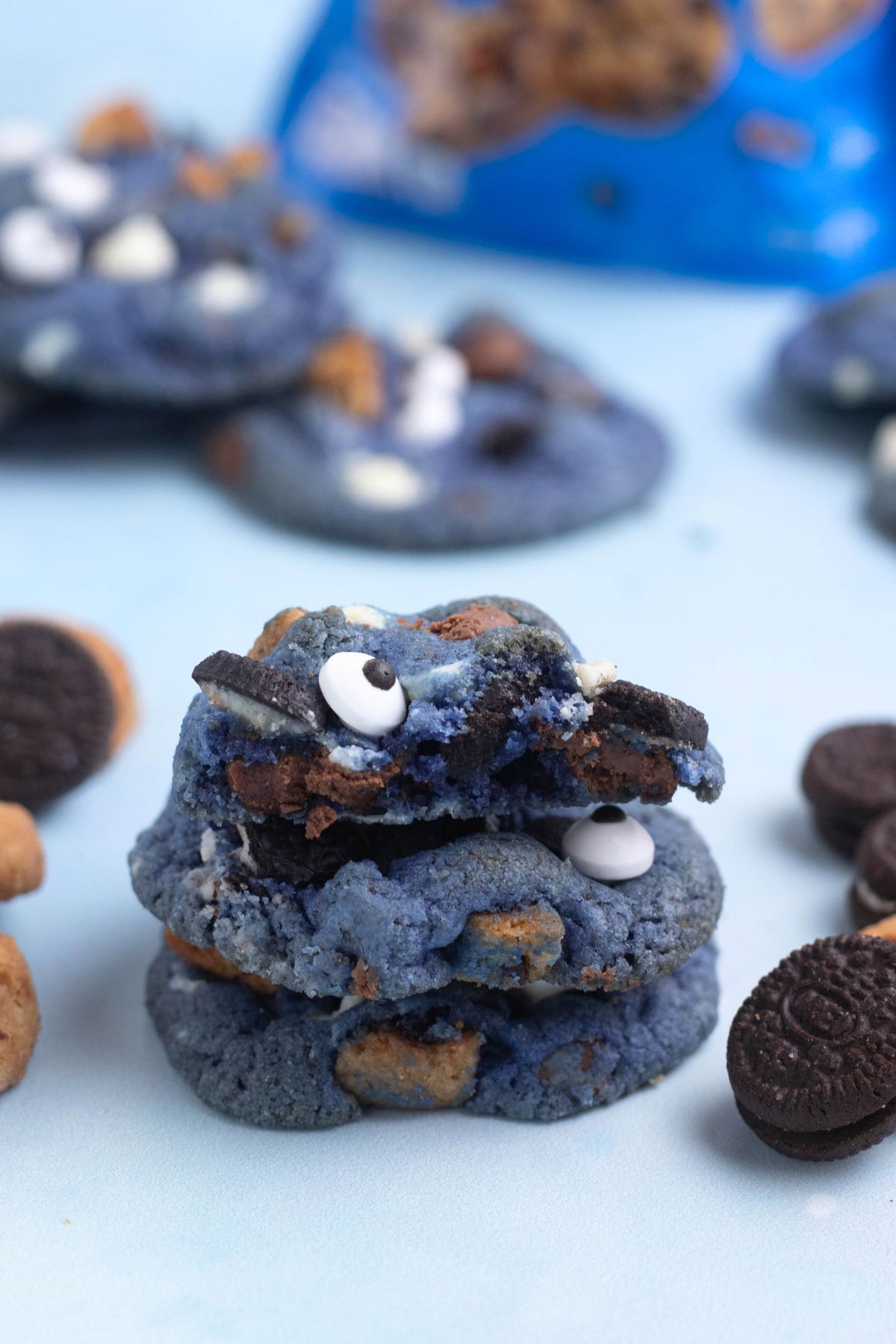 Bright blue cookie monster cookies stacked on a blue table.