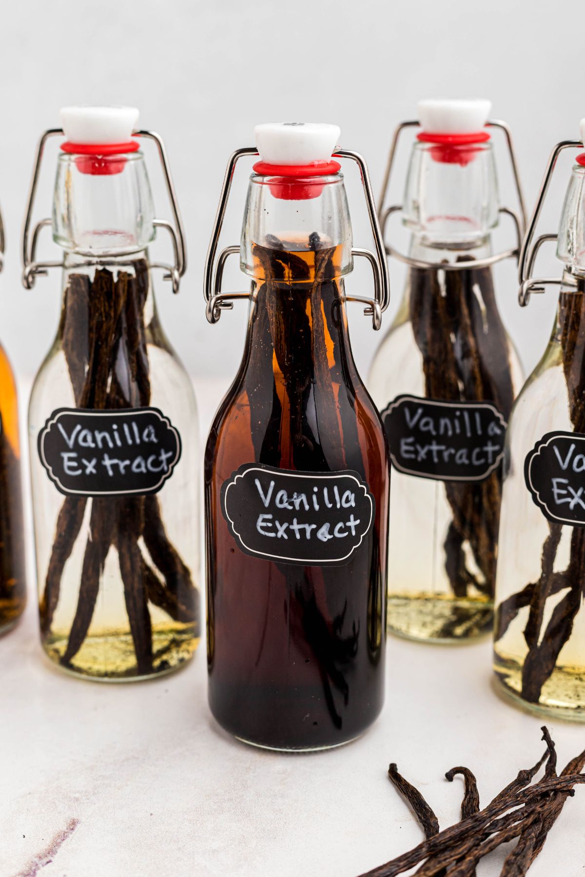 Small glass bottle of homemade vanilla on a white marble table. 