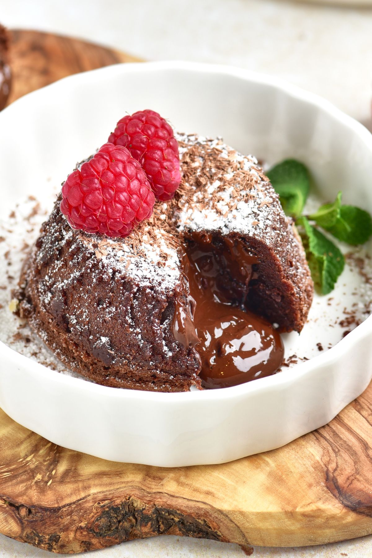 Chocolate mini cake with gooey center coming out onto a white plate. 