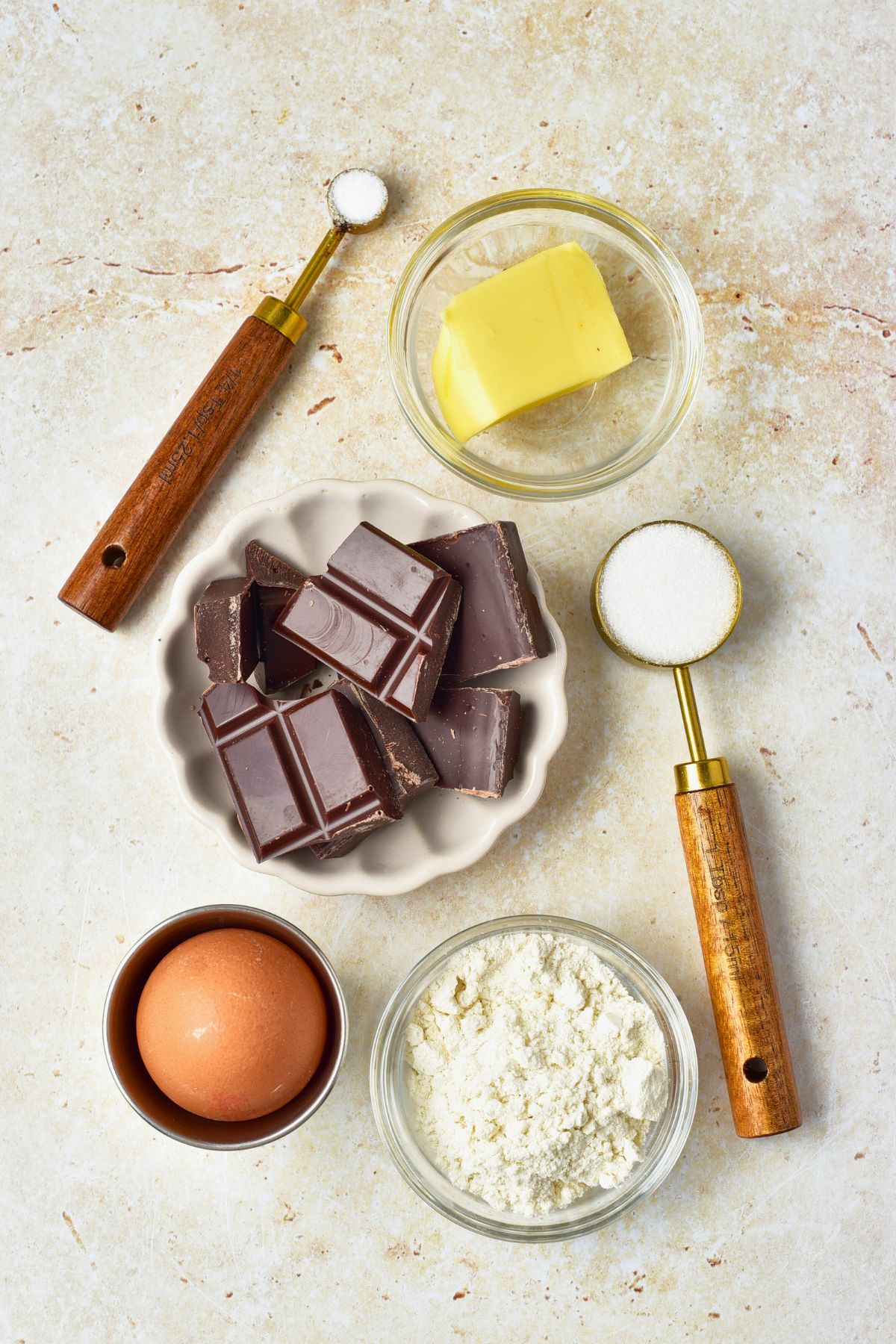 Ingredients needed to make lava cake measured into small bowls on a marble table. 