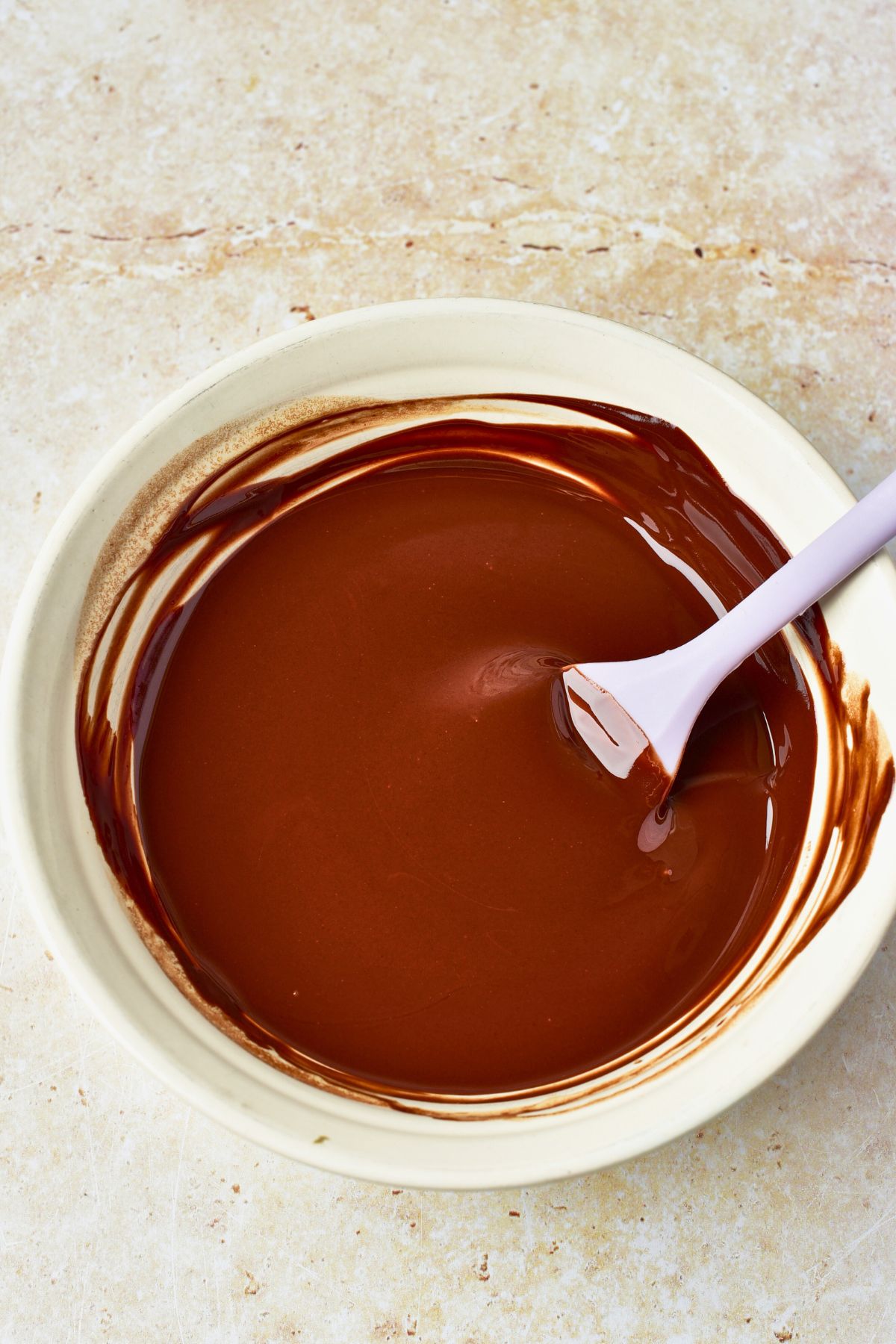 Melted chocolate in a white bowl with a spoon. 