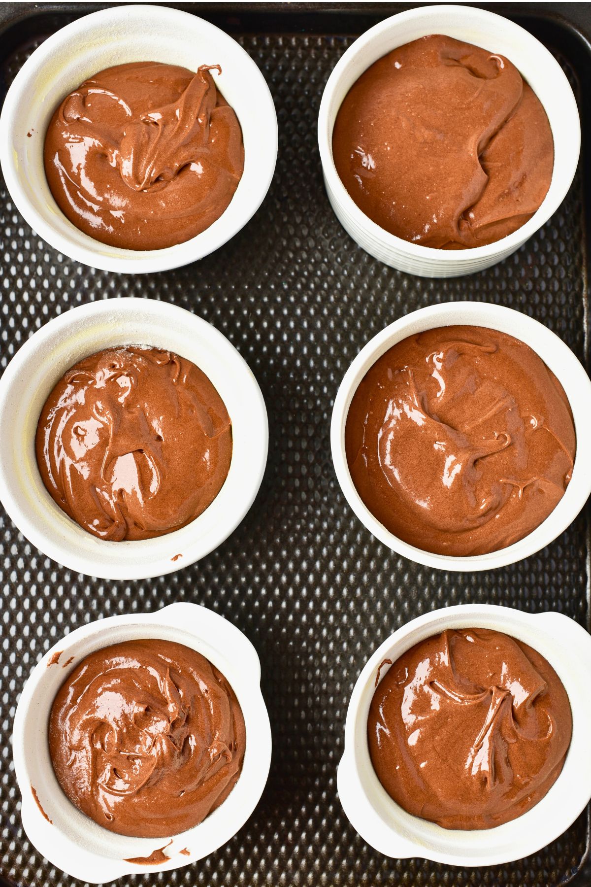 Six ramekins filled with chocolate cake batter, filled with melted chocolate inside.