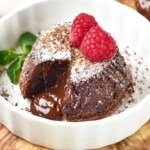 Chocolate mini cake with gooey center coming out onto a white plate.