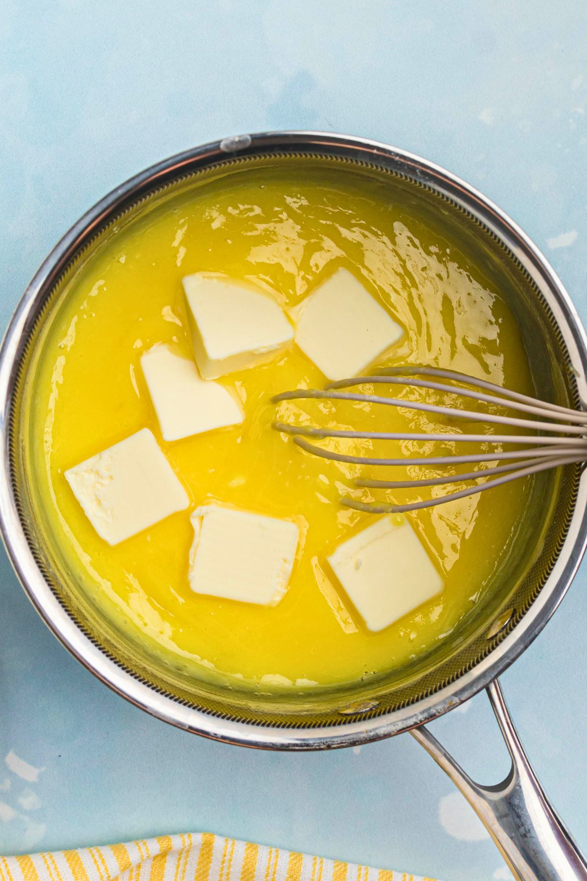 Butter being added to lemon curd in saucepan.