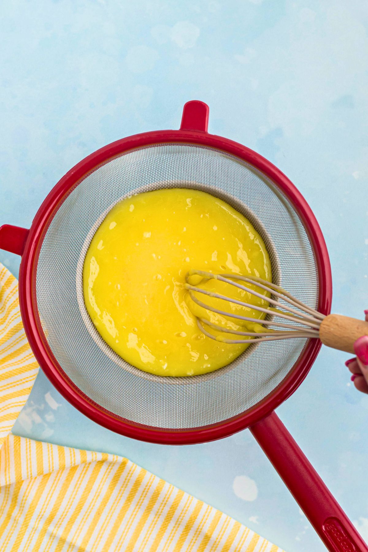 Lemon curd being strained to remove any pieces so it's smooth and creamy. 