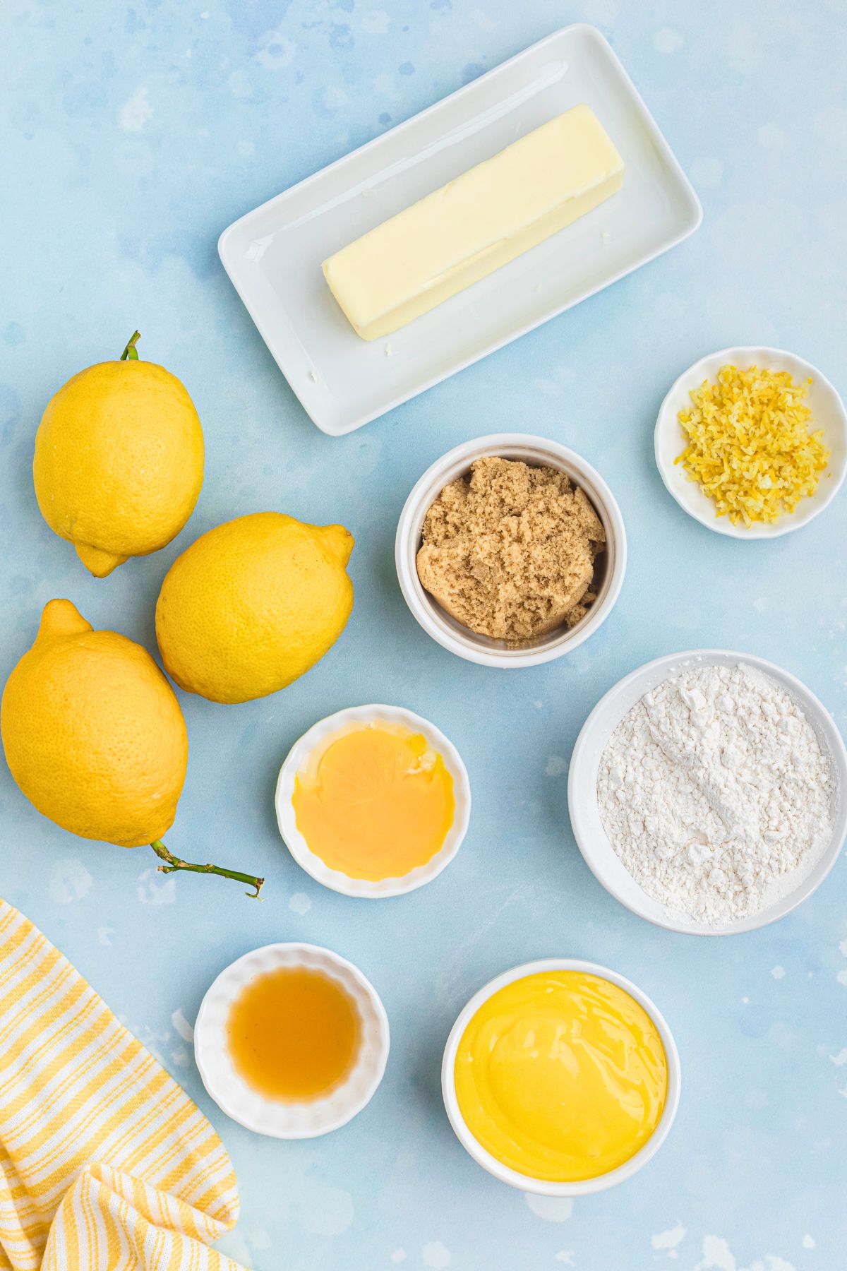 Ingredients needed to make lemon curd cookies, measured onto a light blue countertop.