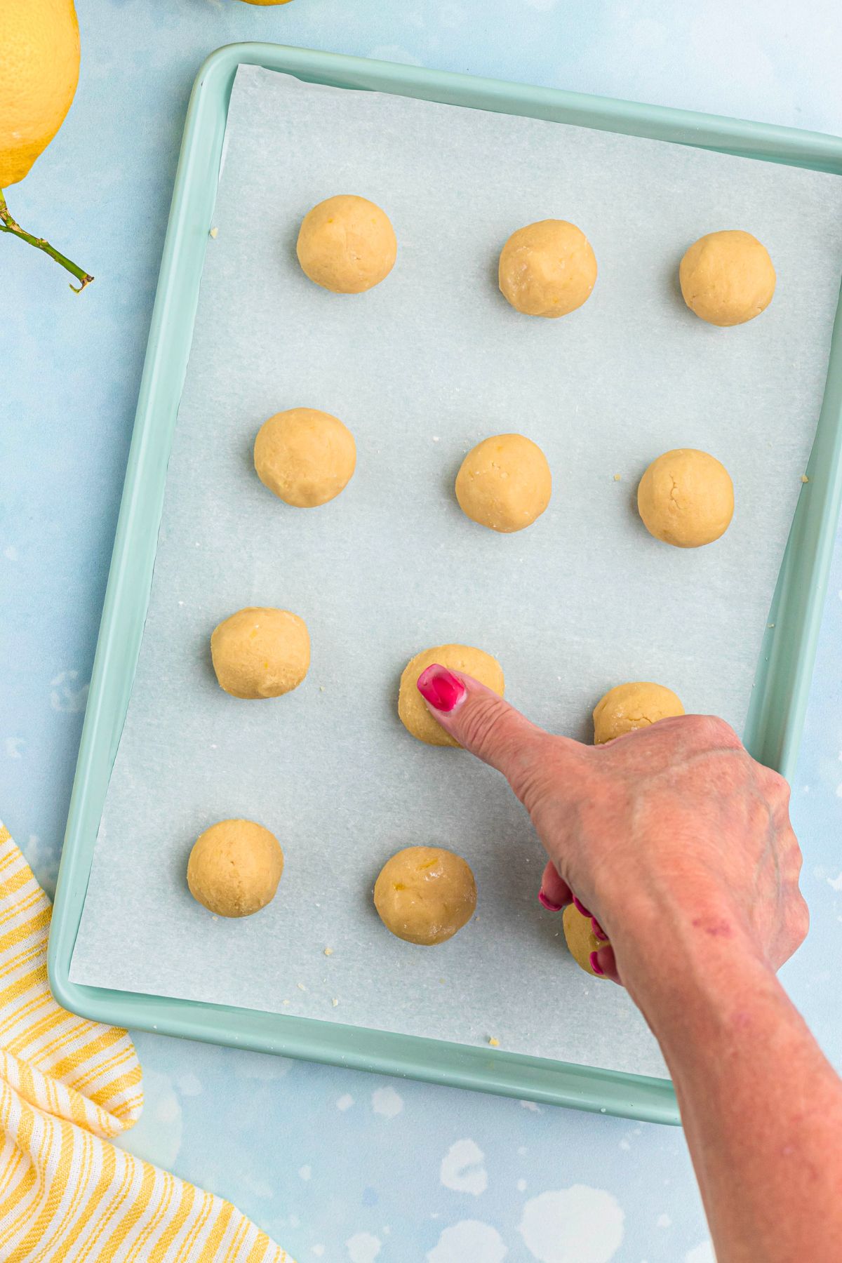 Thumb being used to make indent on top of cookie dough for lemon curd drop. 