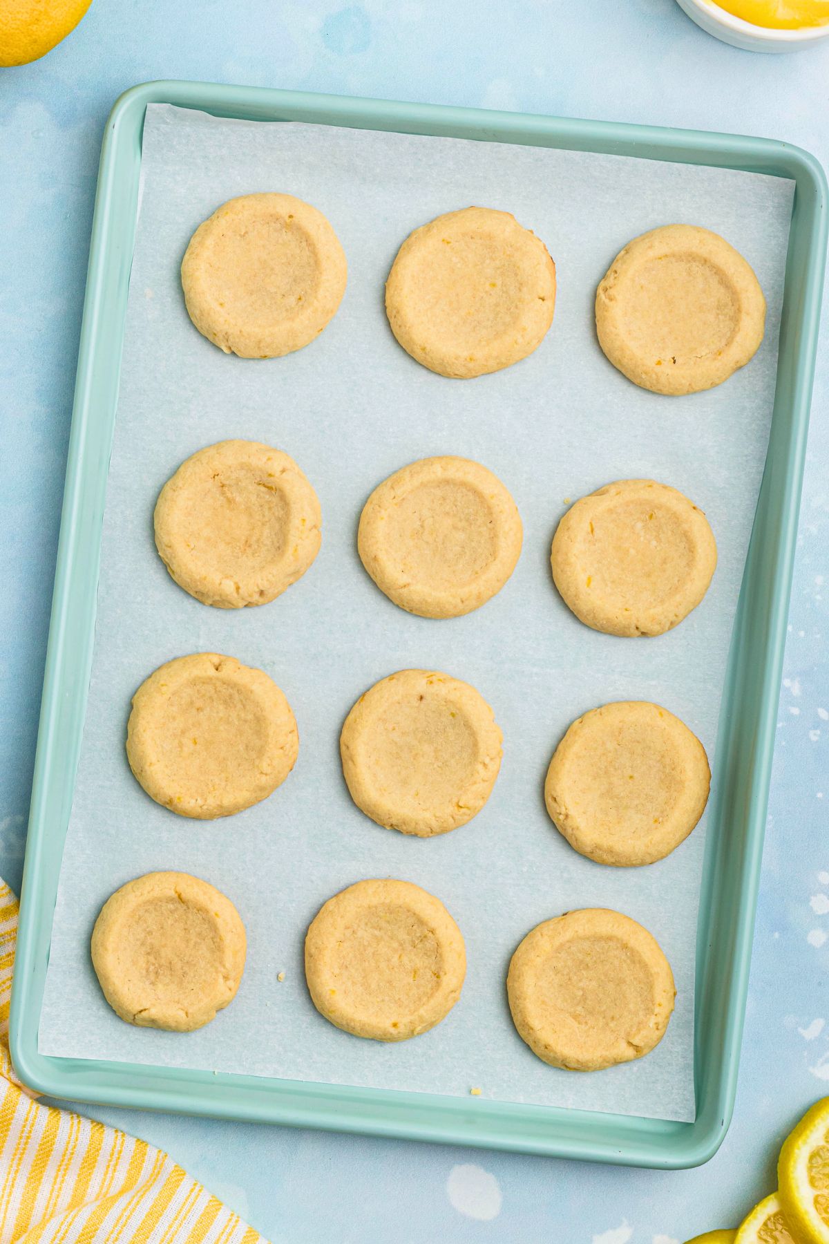 Unbaked cookies with small indentations on baking sheet lined with parchment paper. 