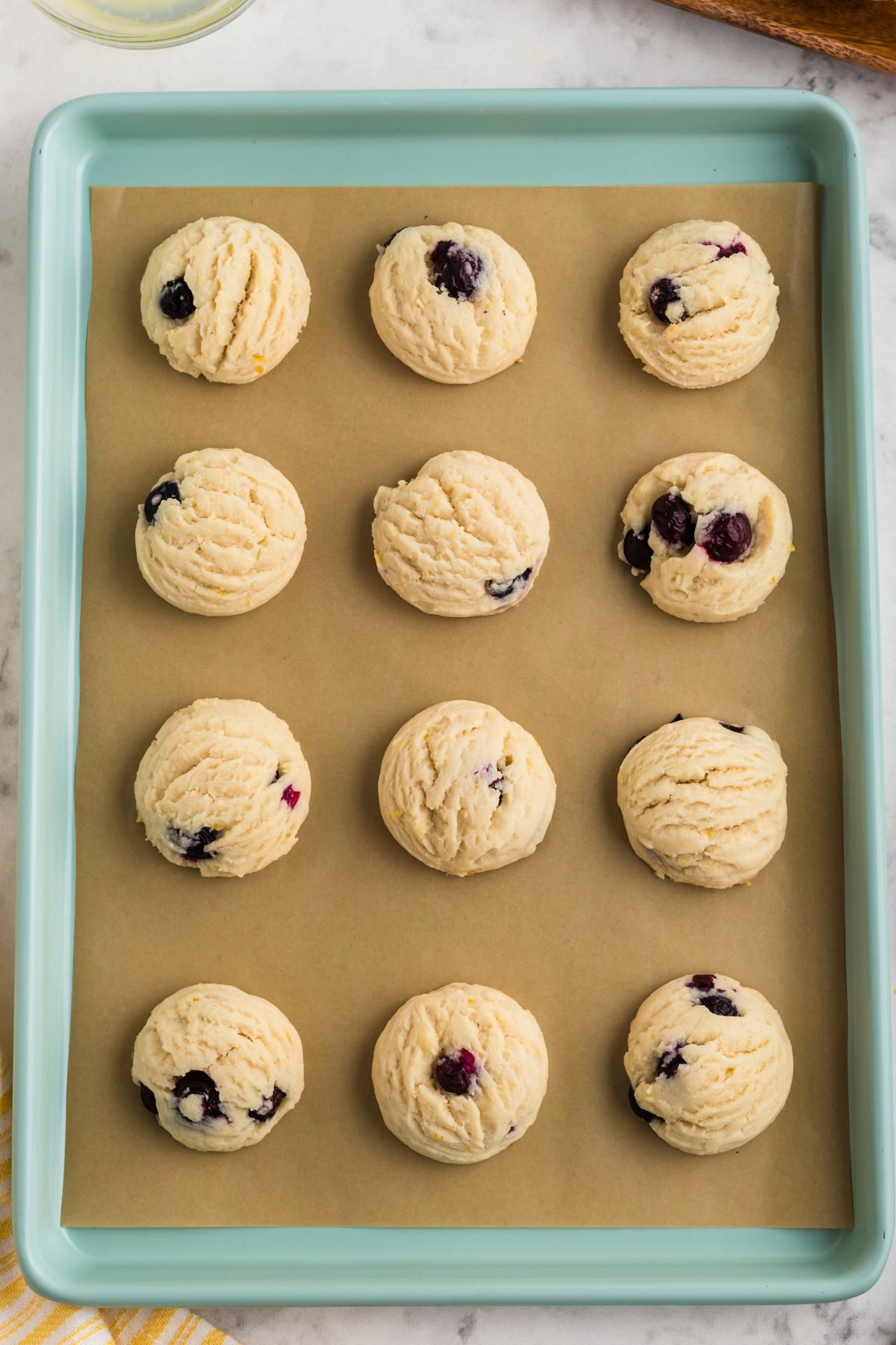 Freshly baked lemon blueberry cookies on a baking sheet. 