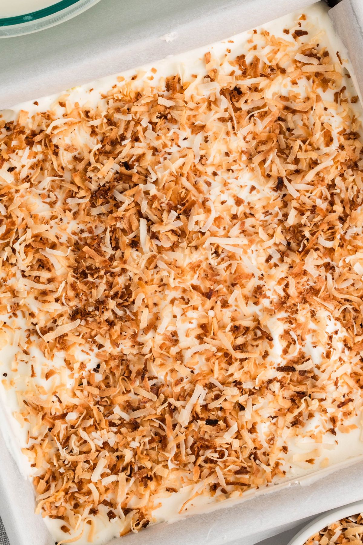 Pie spread in an 8x8 square baking pan, topped with toasted coconut. 