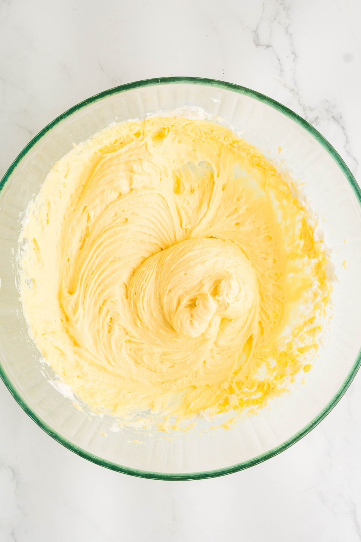 Creamy filling for pie being mixed together in a clear glass bowl. 