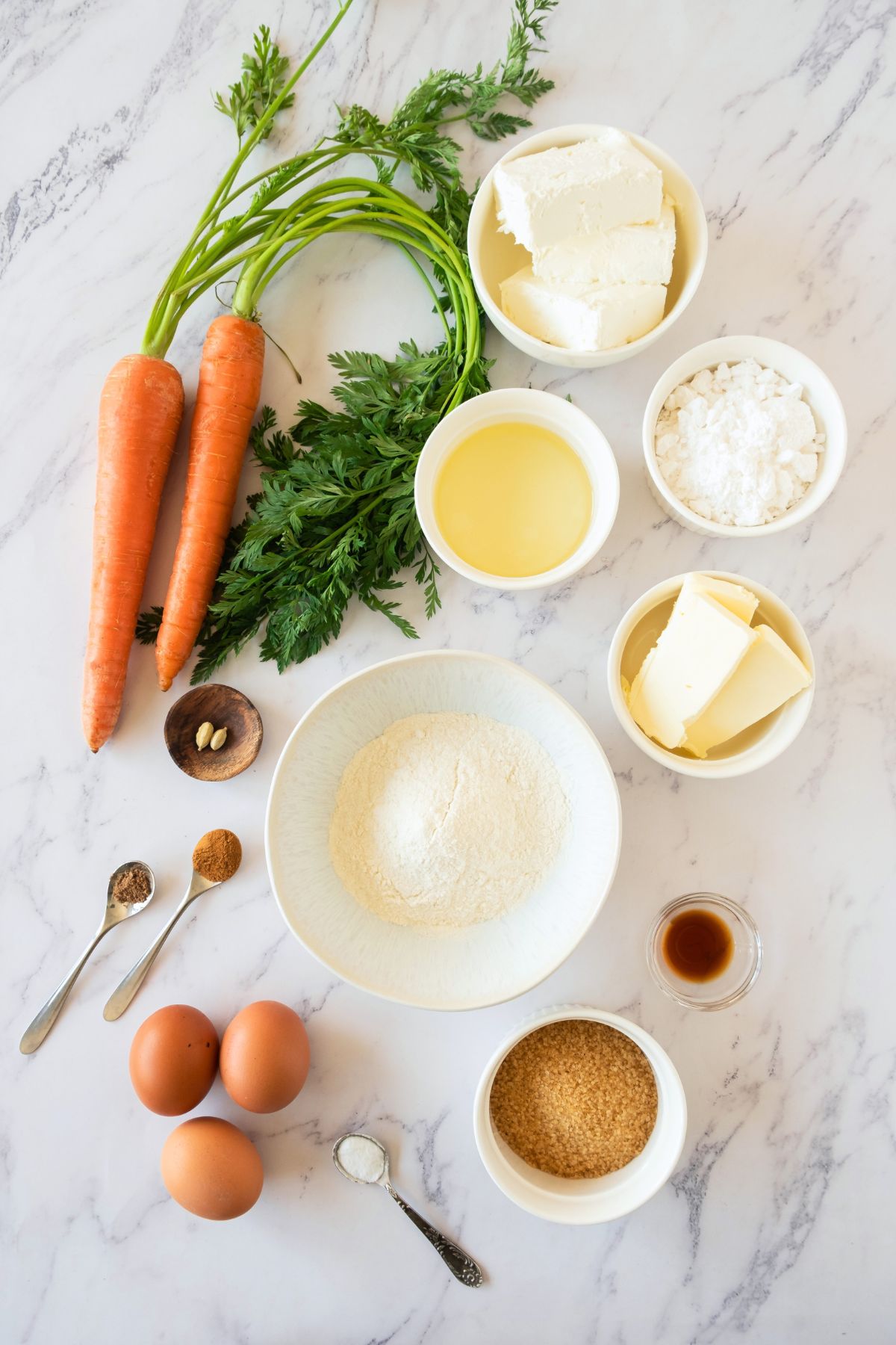 Carrot cake roll ingredients measured into small bowls on a marble table. 