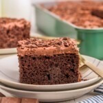 Chocolate poke cake on a plate with bottles of milk behind the plate.